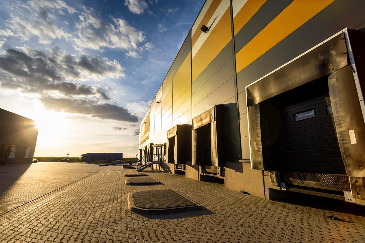 A row of covered loading bays along a distribution warehouse at sunset