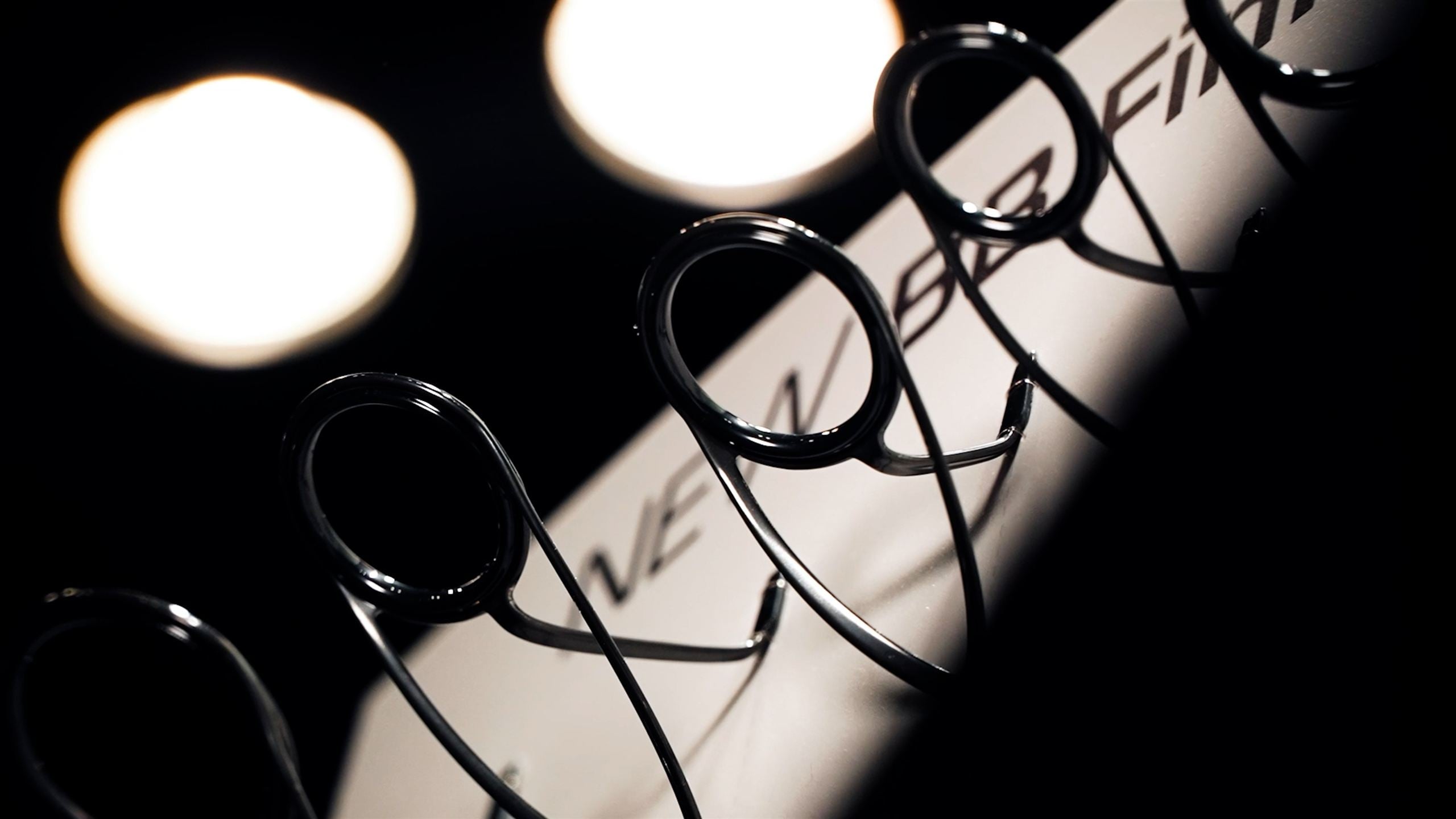 Fuji rod guides in silhouette against a lit display