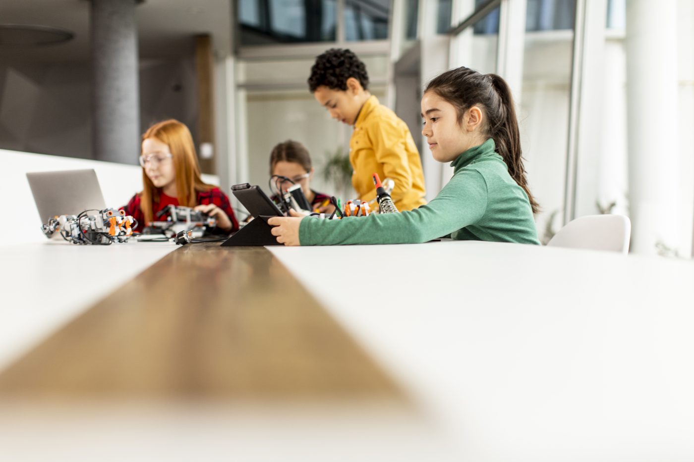 Children building robotics kits at a long table