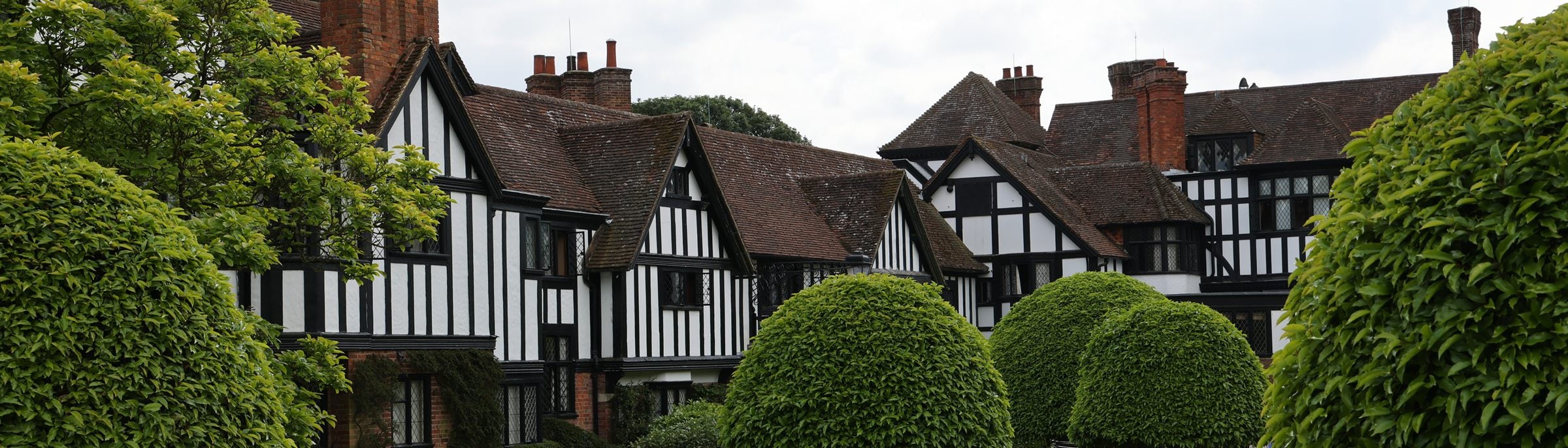 The half-timbered gables and red-brick chimneys of Ascott House near Wing, rising behind clipped topiary