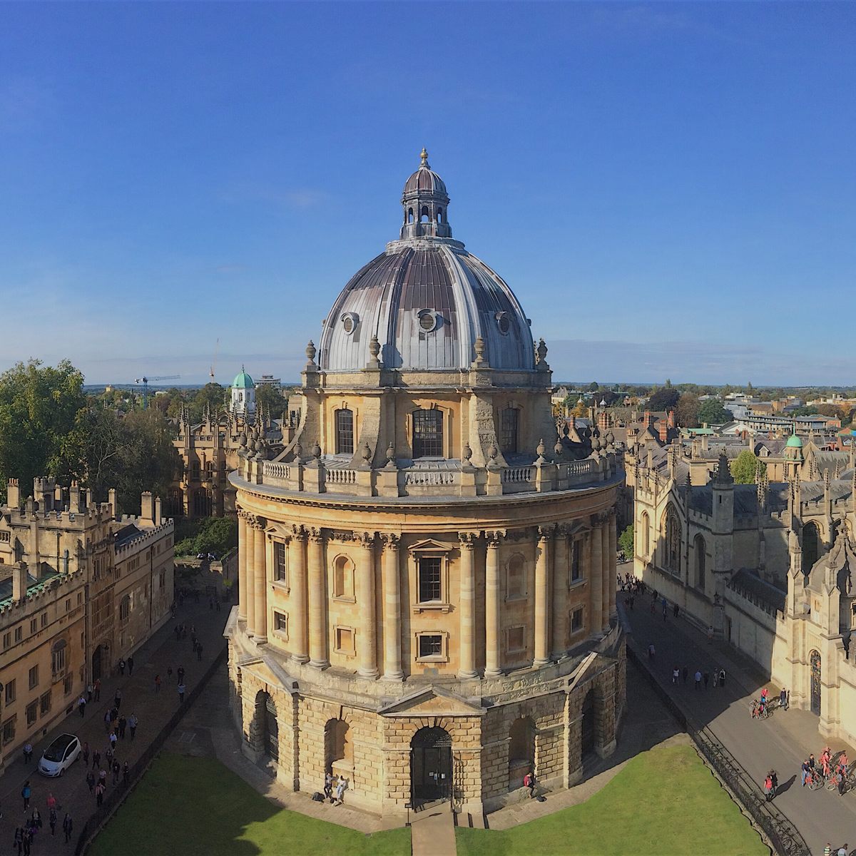 The Radcliffe Camera seen from above, its lead dome and honey-coloured stone ringed by the colleges of central Oxford under a clear sky