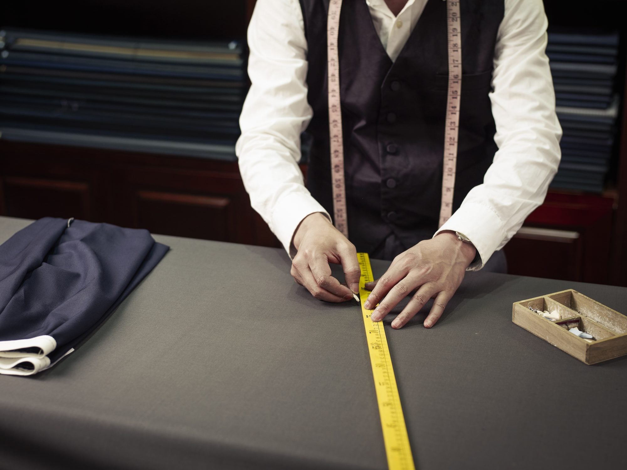A tailor measuring cloth on a cutting table