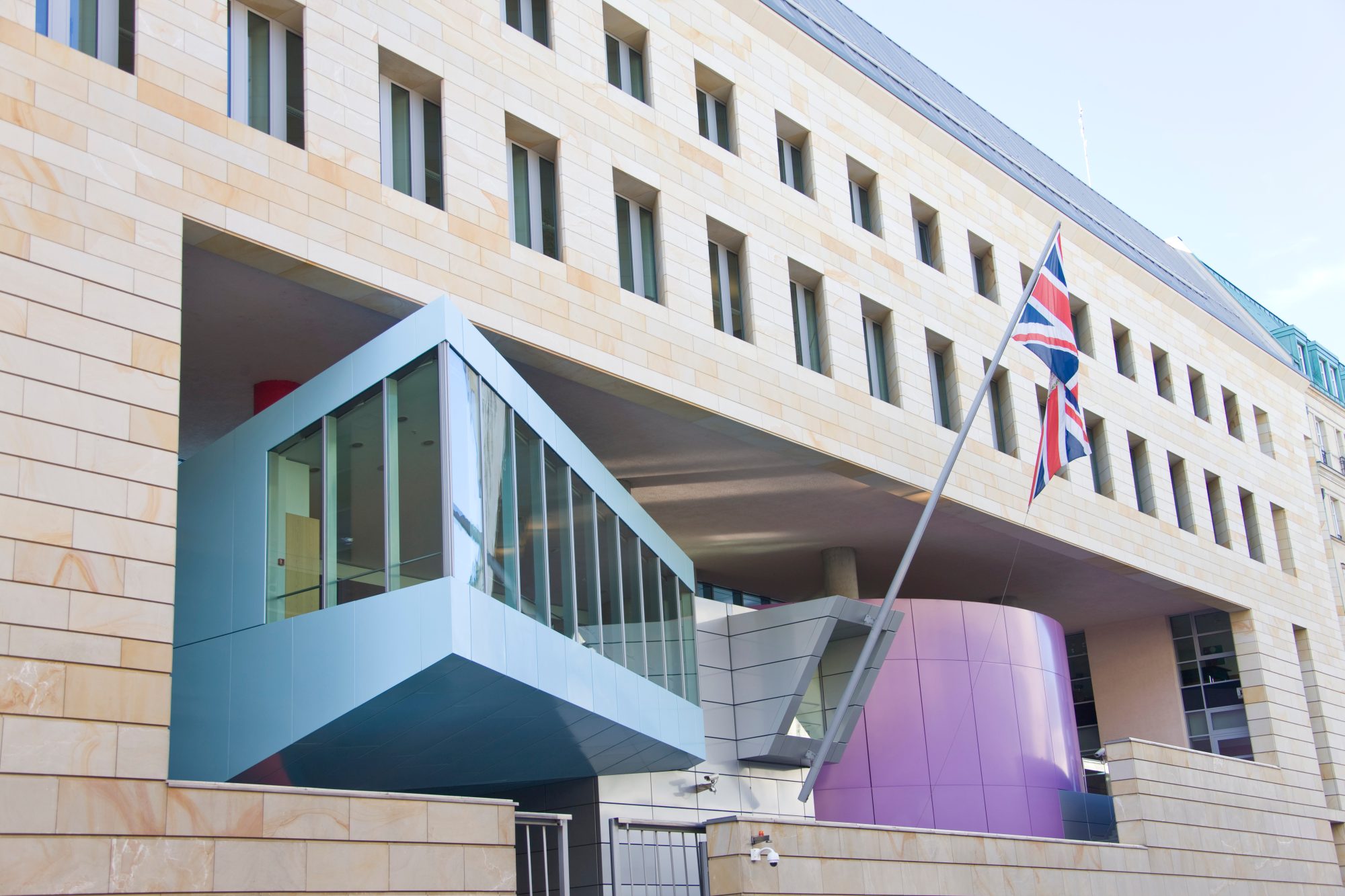 A low angle on the British Embassy in Berlin, its sandstone facade and projecting glass box under a flag