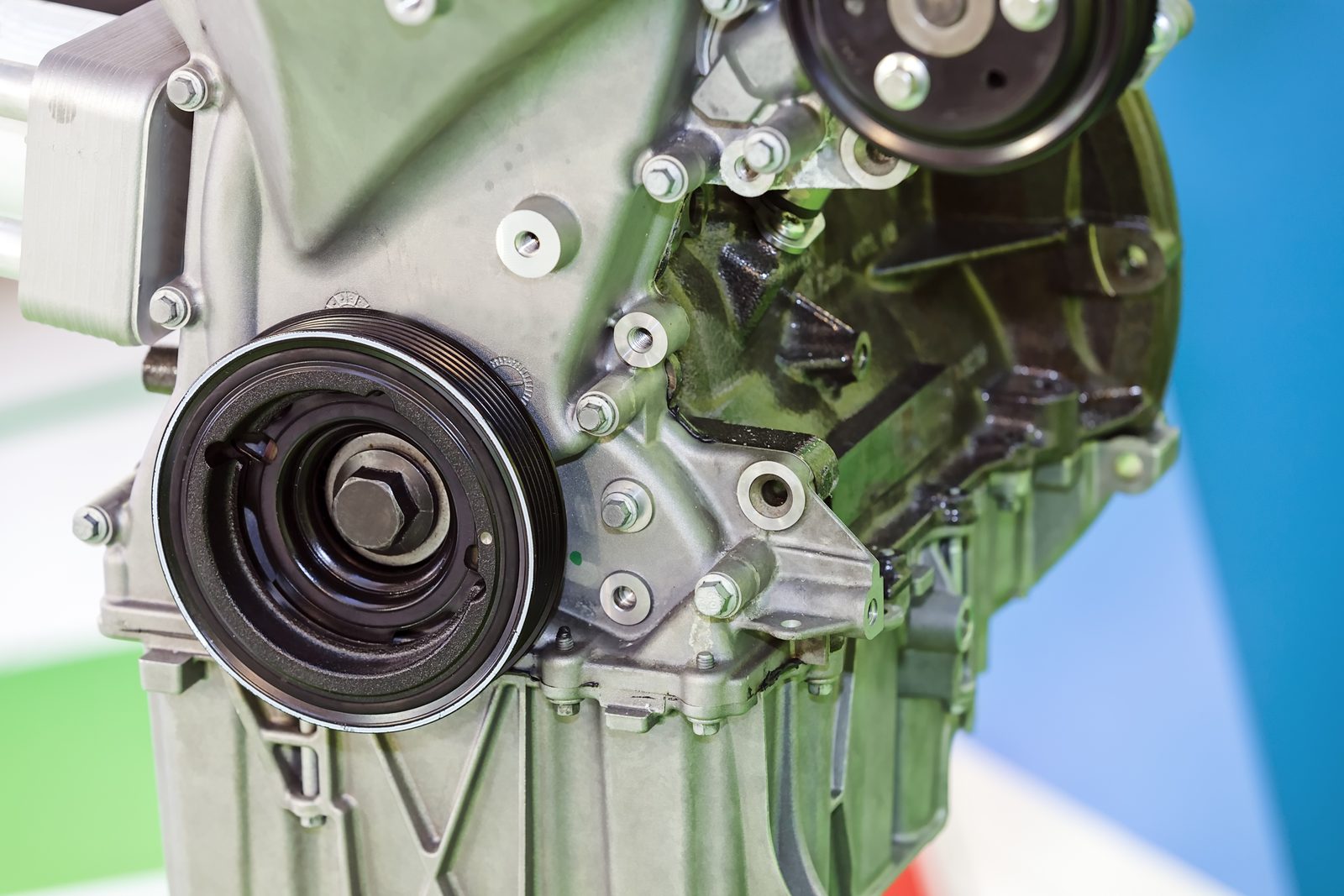 A stripped car engine block, crankshaft pulley and timing cover exposed