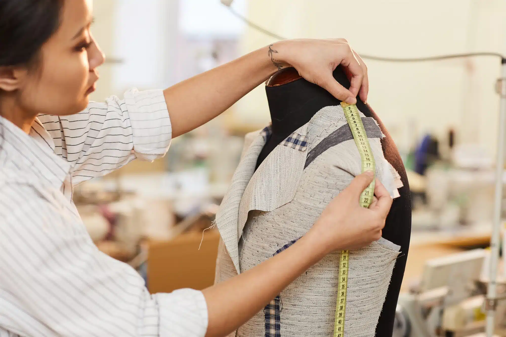 A dressmaker measuring fabric on a dress form
