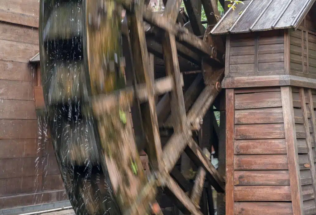 A wooden waterwheel turning under falling water