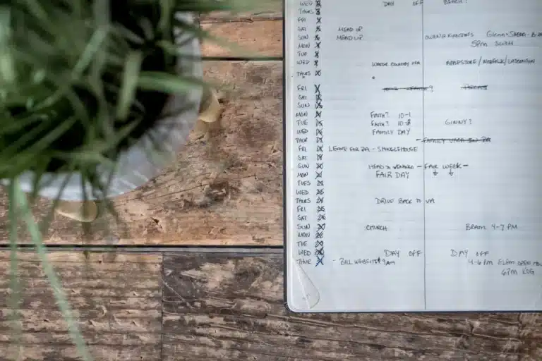 An open planner with dates written down the margin, on a wooden table